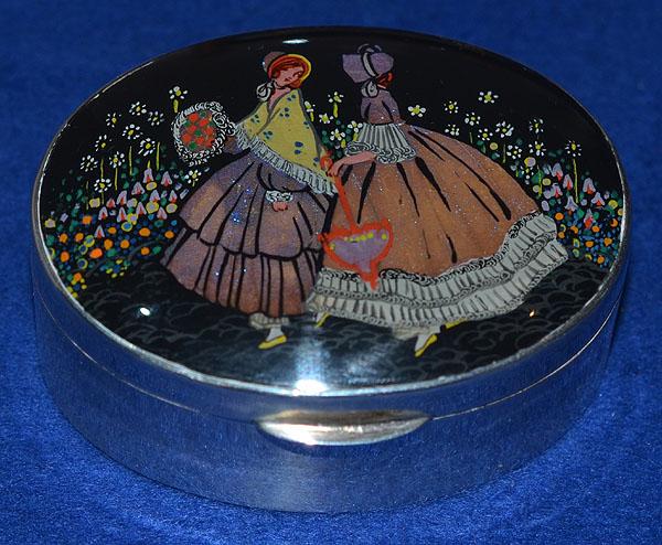 SILVER TRINKET BOX DECORATED WITH COLOURED DESIGN OF TWO LADY'S IN VICTORIAN STYLE CLOTHING.