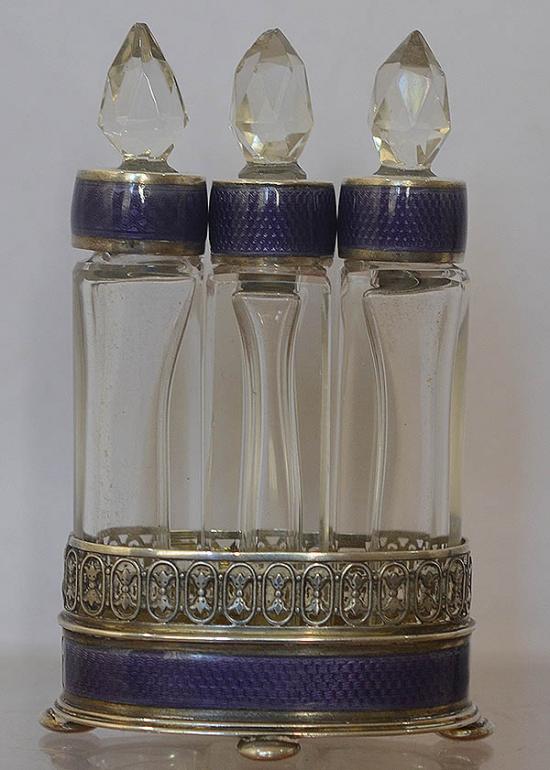 SUPERB SET OF THREE SILVER, ENAMEL AND GLASS PERFUME BOTTLES IN MATCHING HOLDER.