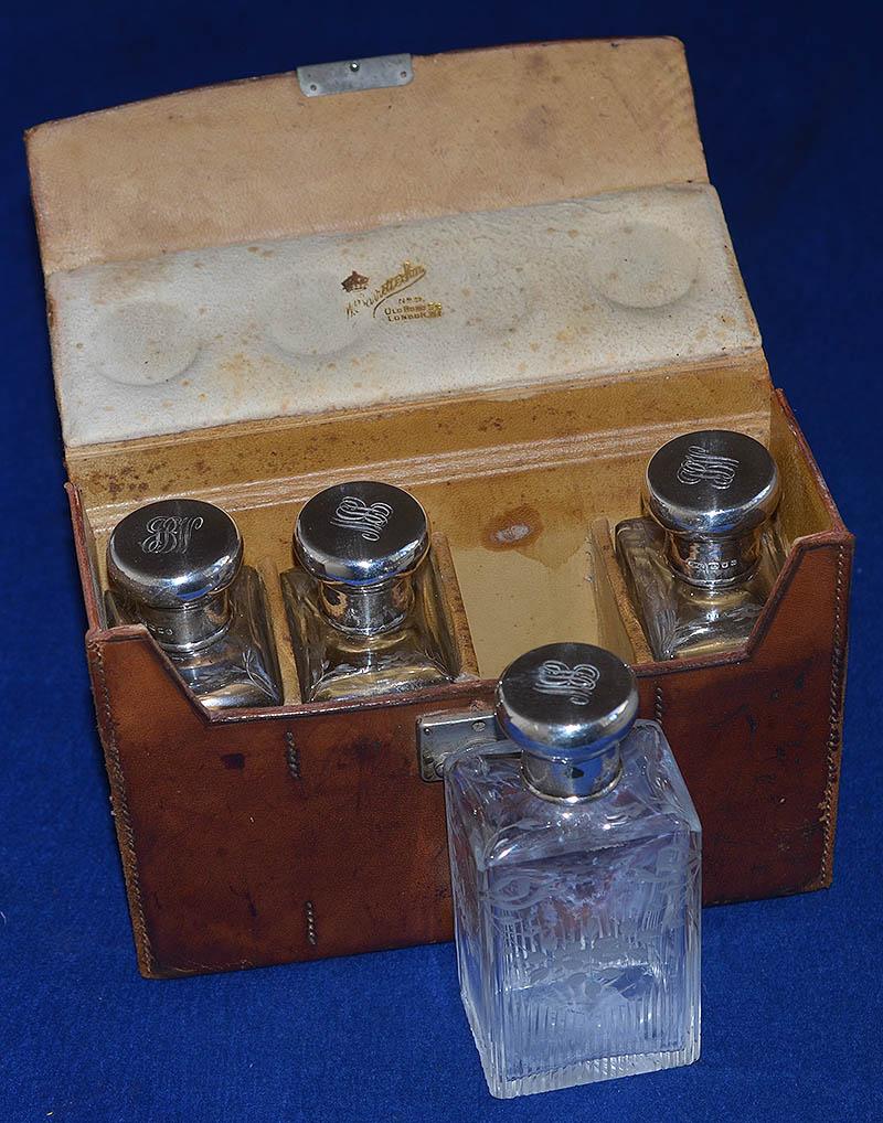 CASED SET OF FOUR ENGLISH SILVER AND GLASS SCENT BOTTLES.